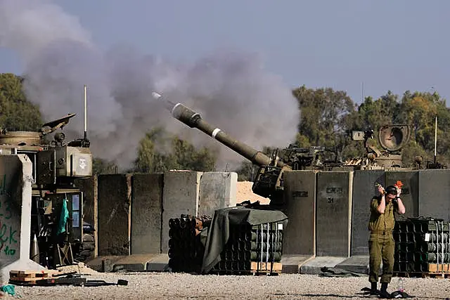 An Israeli soldier covers his ears as an artillery gunner fires into the Gaza Strip from a position in southern Israel