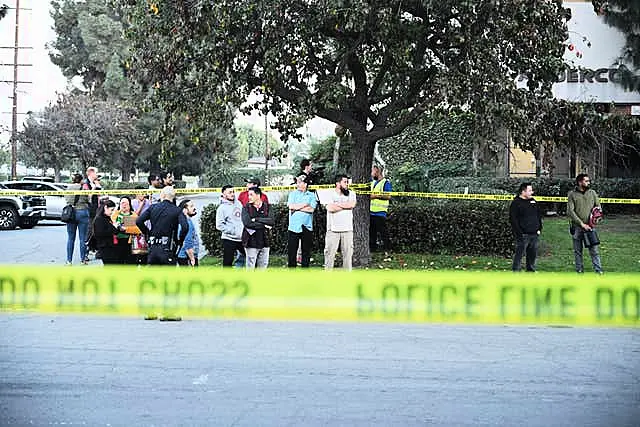 Workers stand near police lines at the scene of a plane crash in Fullerton, Southern California