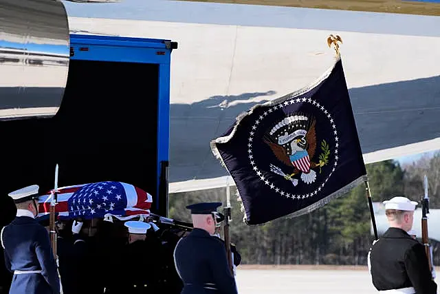 The flag-draped casket of former president Jimmy Carter is placed onto Special Air Mission 39