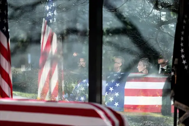 Family members are reflected as they listen during a service at the flag-draped coffin of former US president Jimmy Carter at the Jimmy Carter Presidential Library and Museum in Atlanta 