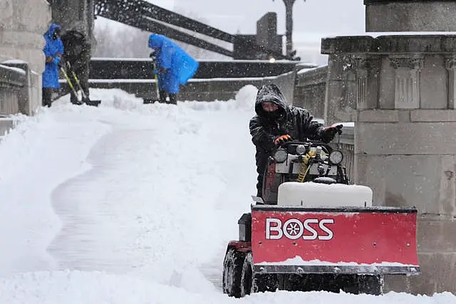 Workers clear snow from a walkway 