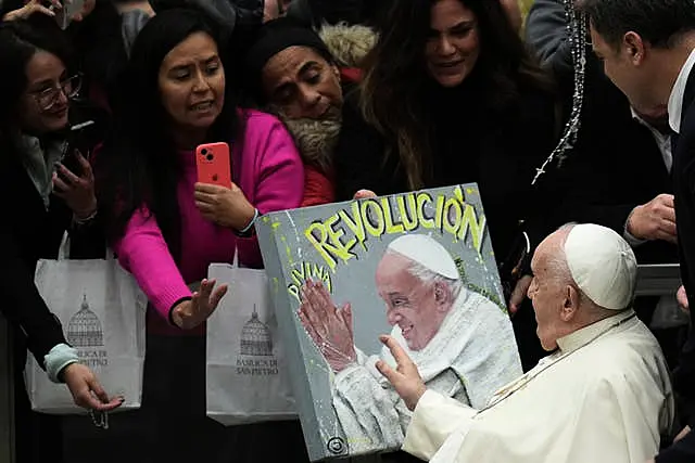 Pope Francis passes in front of a painting with his portrait 