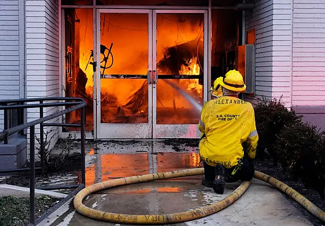 Firefighters aim a hose at the entrance to a Bank of America branch engulfed in flames in Pasadena