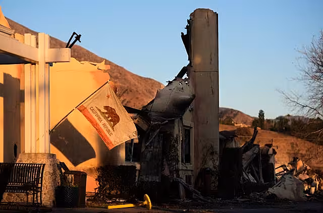 A California state flag hangs outside the charred remains of the Terraces at Park Marino assisted living facility in Pasadena, California