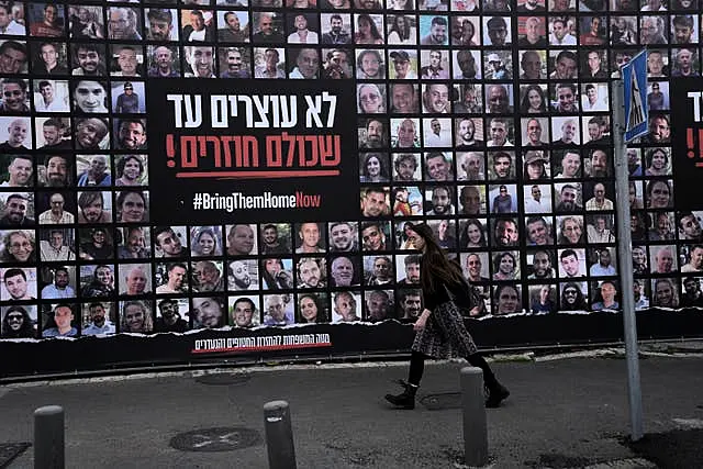 A woman in Jerusalem walks past photos of hostages held by Hamas in the Gaza Strip 