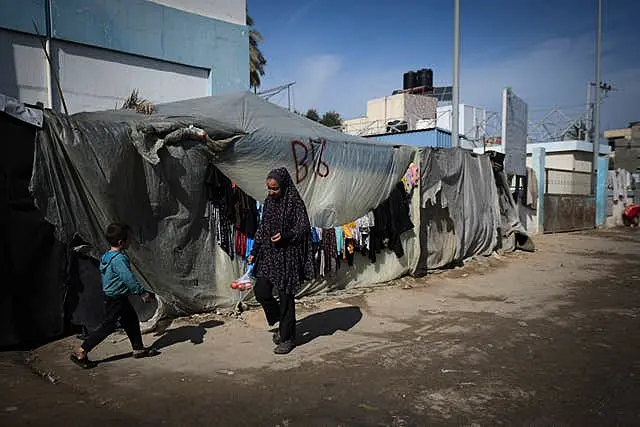 A woman and a child walk outside their tent at a camp for displaced Palestinians in Deir al-Balah, central Gaza Strip