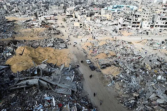 Palestinians walk through the destruction by the Israeli air and ground offensive in Rafah, as a ceasefire deal between Israel and Hamas went into effect