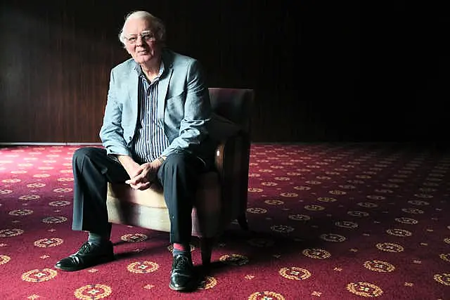 Austin Currie sitting in a chair on a red carpet