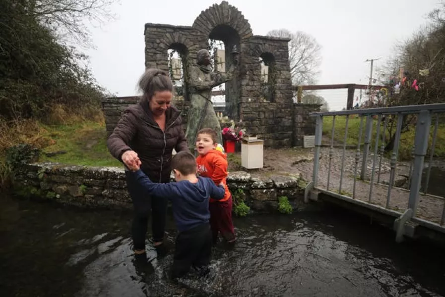 Christine Barry and her sons Sean four and two-year-old Oran bless themselves in the water as they visit St Brigid’s holy well in Co Kildare to mark St Brigids Day (Niall Carson/PA)