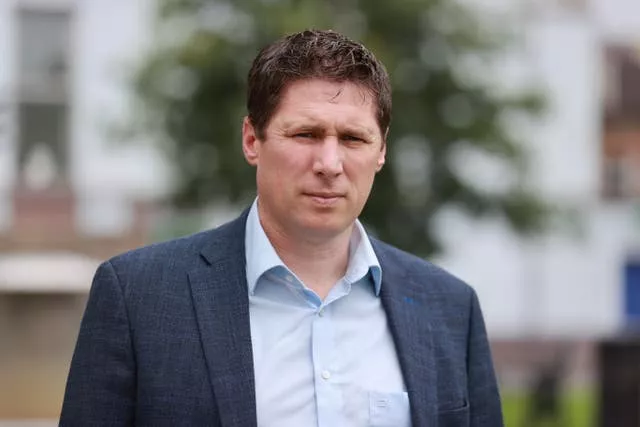 A man with a blue jacket and open-neck shirt