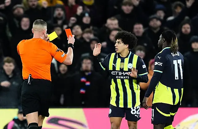 Referee Chris Graham shows a red card to Manchester City’s Rico Lewis 