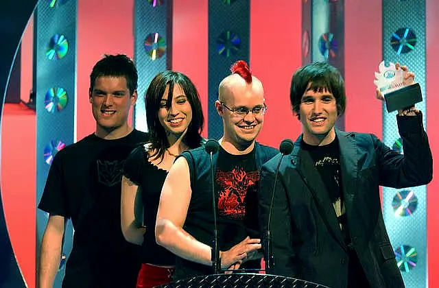 Three young men and a young woman, one of the men holding up an award