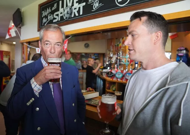 Nigel Farage (left) drinking a pint while standing at a bar with the new Reform MP for South Basildon and East Thurrock, James McMurdock