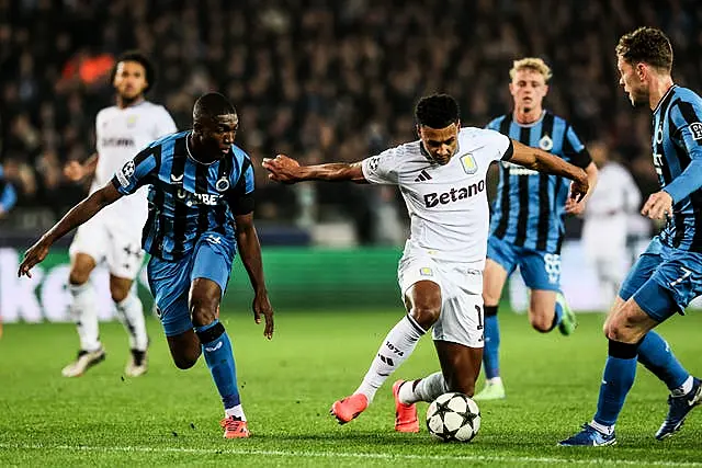 Ollie Watkins attempts to dribble the ball past two Club Brugge players