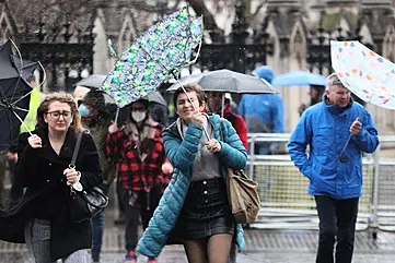 Members of the public brace themselves in the wind and wet weather in Westminster, central London