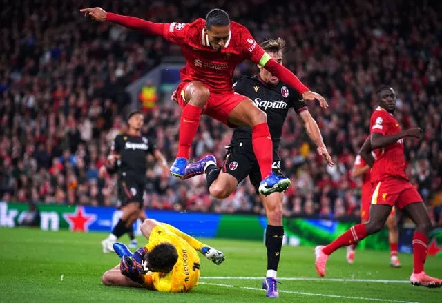 Virgil van Dijk hurdles over his goalkeeper as Alisson Becker slides to pick up the ball