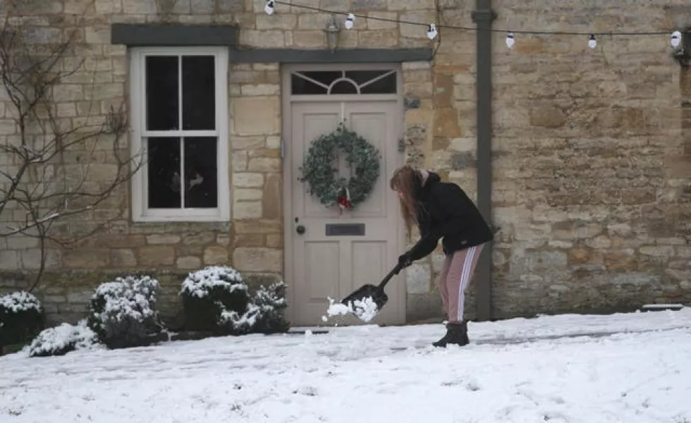 A woman clears snow from pathways 