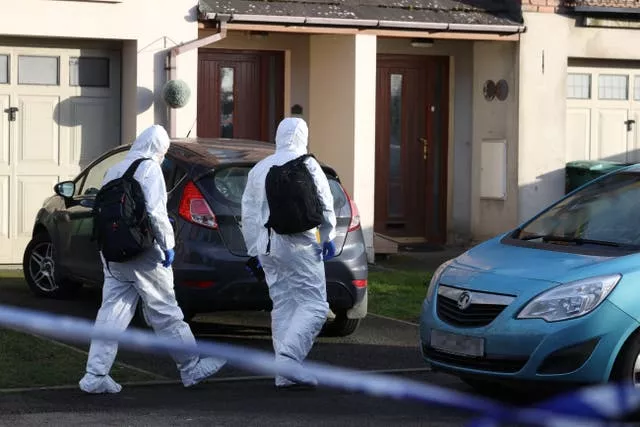 Forensic officers walk into a property in the Silverwood Green area of Lurgan