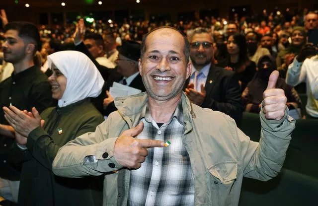 Khaled Kakaa smiling and pointing to an Irish flag badge at a citizenship ceremony at the Convention Centre in Dublin 