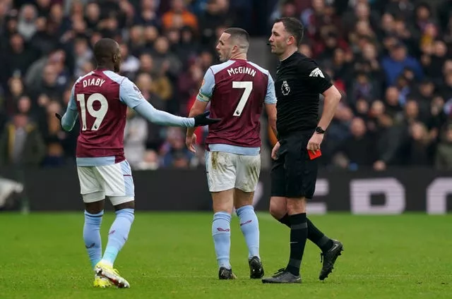 Aston Villa’s John McGinn reacts after being shown a red card by referee Chris Kavanagh, right