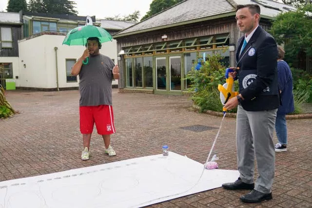 Harvey Price watches as Will Munford, an ajudicator from Guinness World Records, measures his picture of the train (Jacob King/PA)