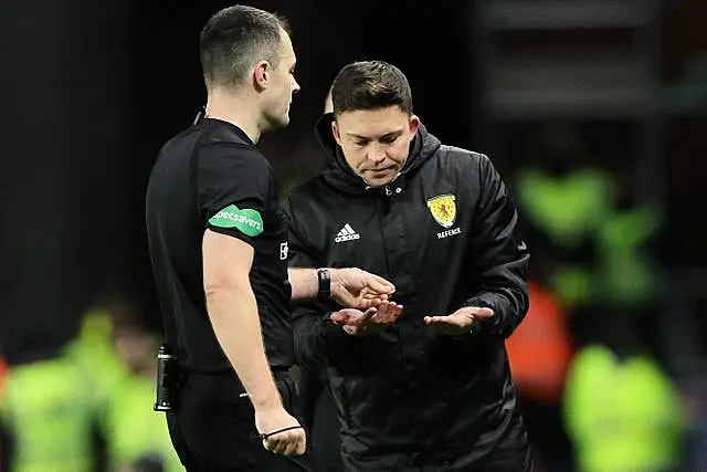 Referee Don Robertson (left) passes an object that was thrown from the crowd towards Celtic’s Arne Engels to a stadium official 