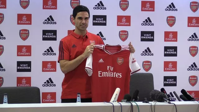 Mikel Arteta holds up an Arsenal shirt during a press conference