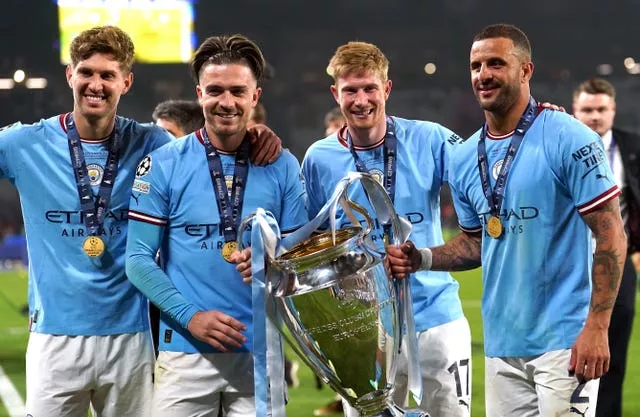 John Stones (left), Jack Grealish, Kevin De Bruyne and Kyle Walker (right) with the trophy