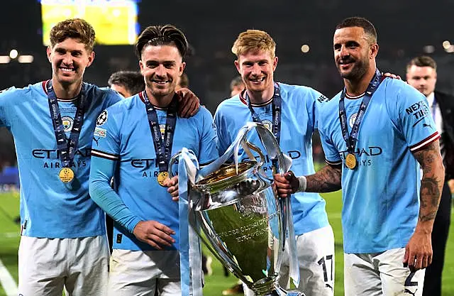 John Stones (left), Jack Grealish, Kevin De Bruyne and Kyle Walker (right) with the trophy