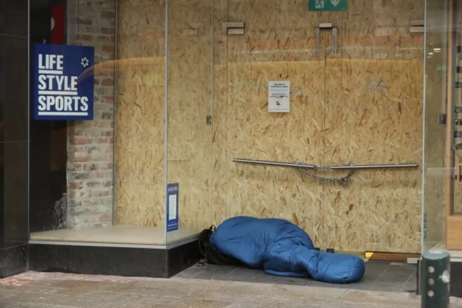 A homeless person sleeps in the doorway of a boarded up shop in Dublin city centre