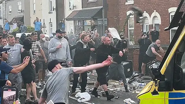 Men in street throwing items at police van