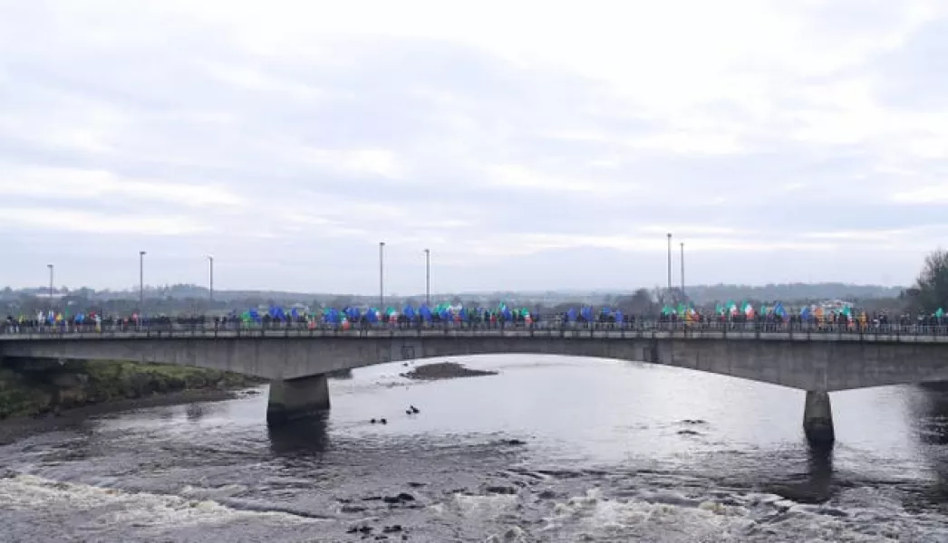 People take part in an Irish unity march as they cross the Lifford Bridge, from Donegal, which marks the border between Strabane in County Tyrone, Northern Ireland, and Lifford in County Donegal in the Republic of Ireland (Niall Carson/File/PA)