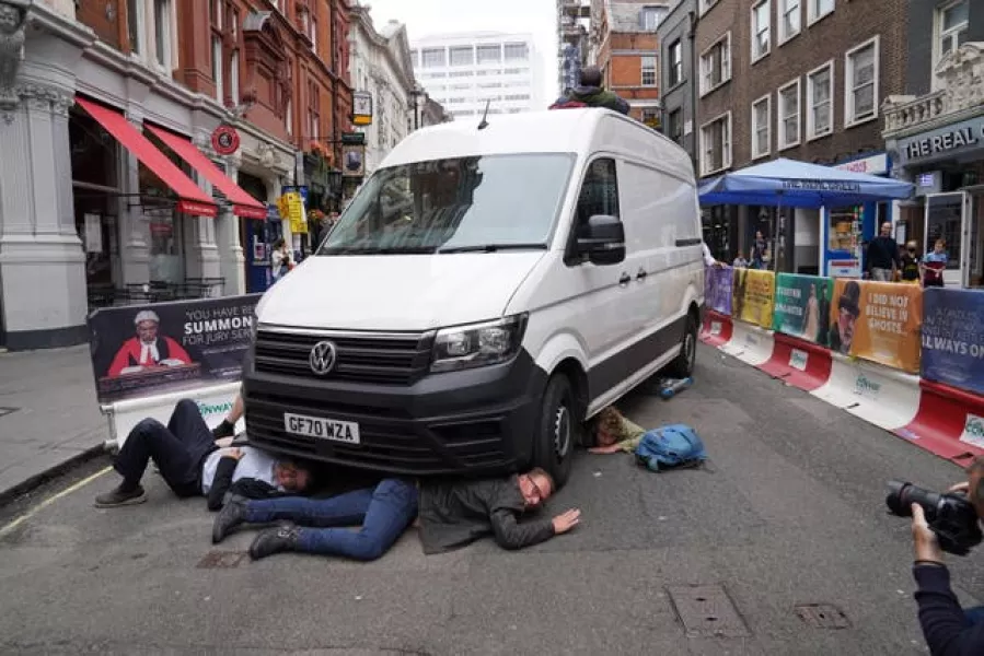 Demonstrators position themselves under a van