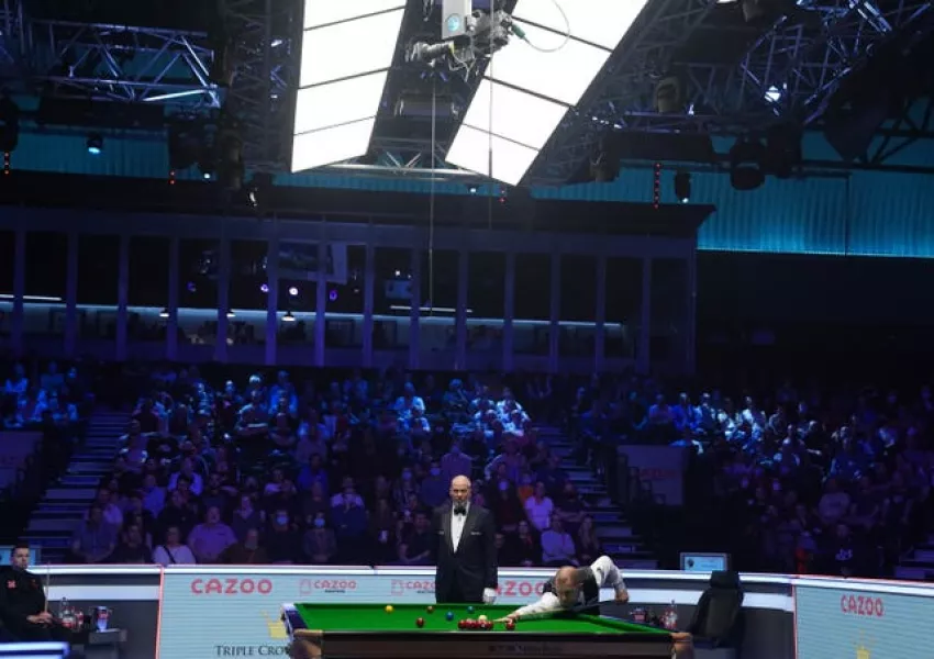 Barry Hawkins compiles a break as Mark Selby, extreme left, looks on