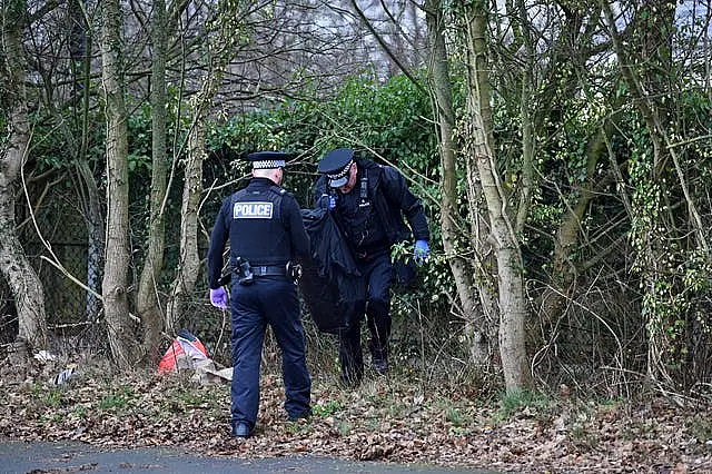 Police officers retrieve police riot equipment left at the scene outside the Suites Hotel in Knowsley, Merseyside