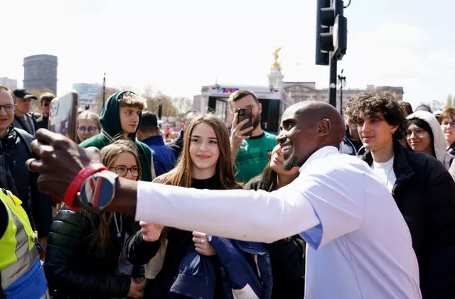 Sir Mo Farah takes photographs with fans in the Buckingham Palace Memorial Gardens ahead of the 2023 London Marathon 