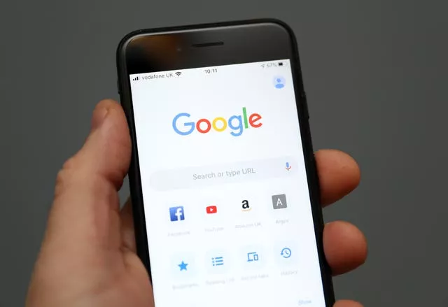 A person holding an iPhone showing the app for Google Chrome search engine