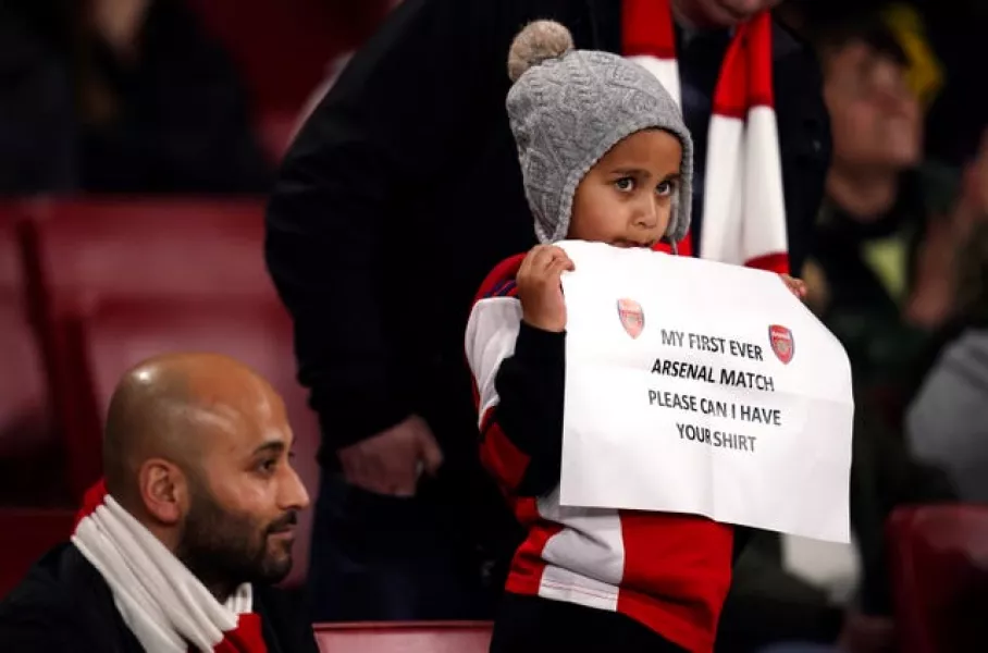 A young Arsenal fan holds up a banner