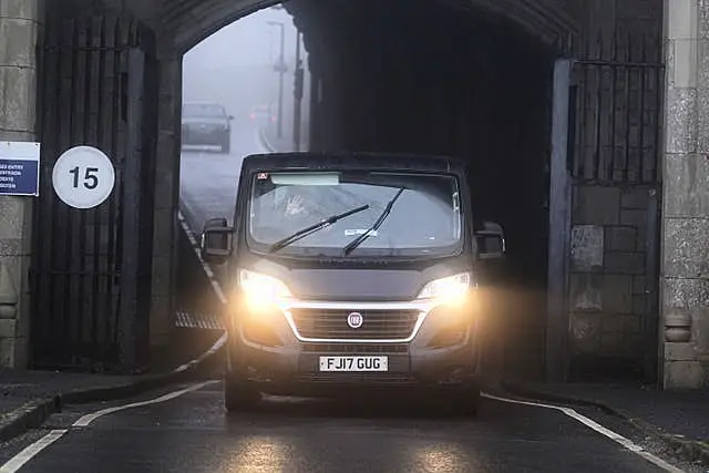 A dark van driving through a stone archway.