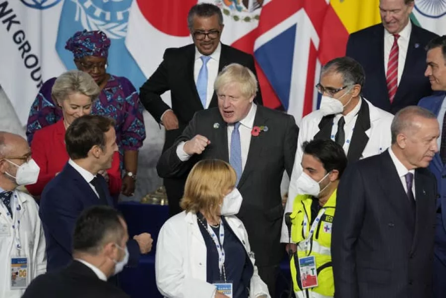 Prime Minister Boris Johnson and French President Emmanuel Macron do a fist bump as they gather with other world leaders gather for a group picture at the La Nuvola conference centre during the G20 summit in Rome, Italy