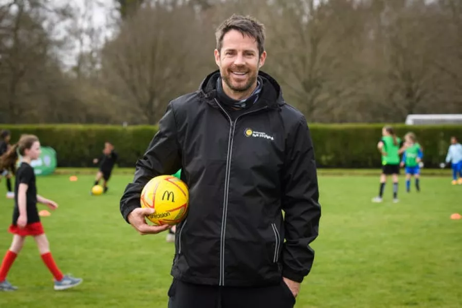 Jamie Redknapp holds a ball at a coaching session for children