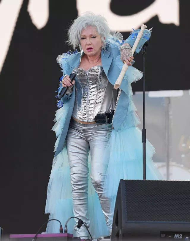 Cyndi Lauper leaning on a microphone stand while on stage at Glastonbury