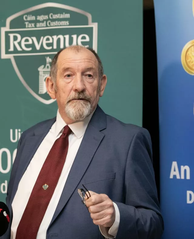 Michael Gilligan in a suit and tie, in front of Revenue signage