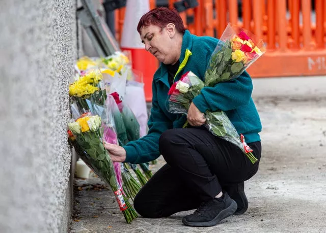 A woman leaves flowers near the scene of the fatal crash