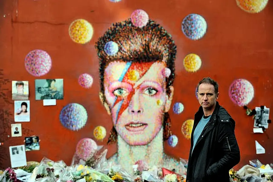 Artist Jimmy C, stands in front of his David Bowie mural artwork