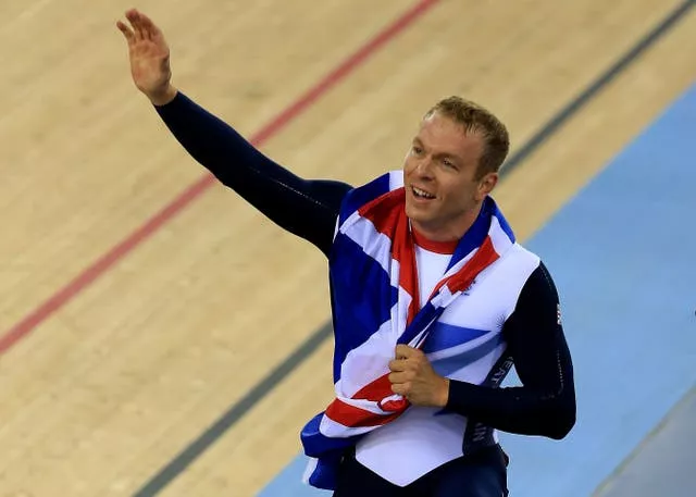 Sir Chris Hoy waves to the velodrome crowd while wearing a Union flag around his shoulders at London 2012