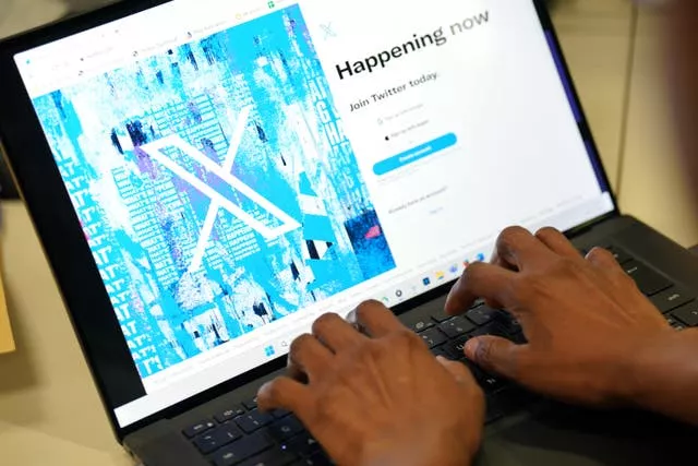 A person uses a keyboard to sign into the X website