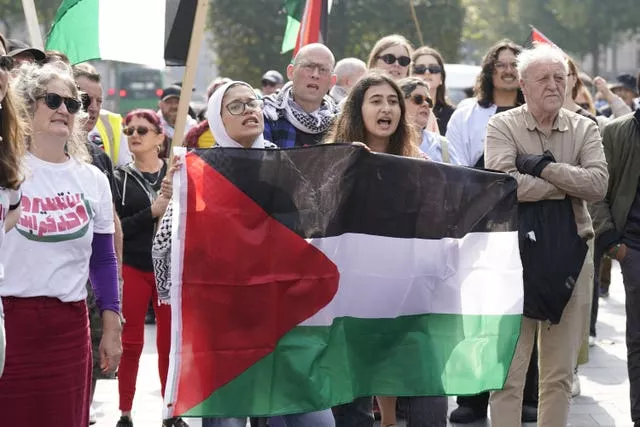 People during a pro-Palestine protest in Dublin, including two young women holding a Palestinian flag