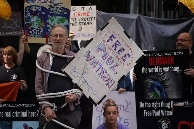 People wrapped in ropes and holding placards take part in a protest outside the Danish embassy in Dublin