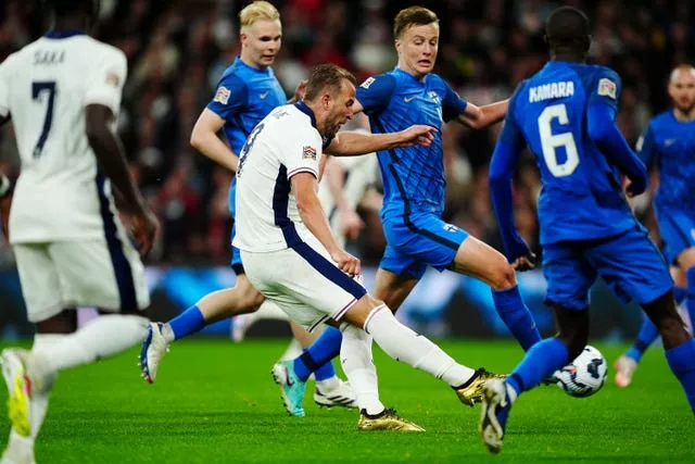 England’s Harry Kane, in gold boots and surrounded by Finland defenders, scores the first goal of his 100th cap